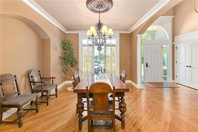 dining room with baseboards, arched walkways, ornamental molding, an inviting chandelier, and light wood-type flooring