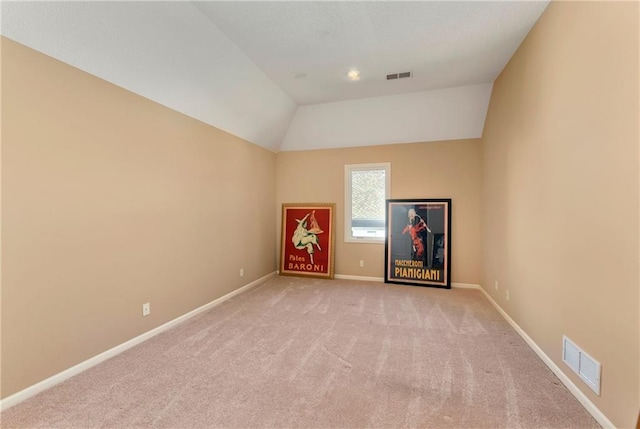 empty room with visible vents, vaulted ceiling, and baseboards