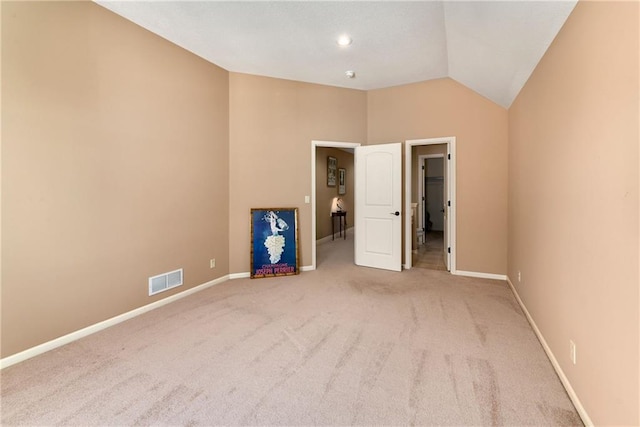 spare room featuring lofted ceiling, carpet flooring, visible vents, and baseboards