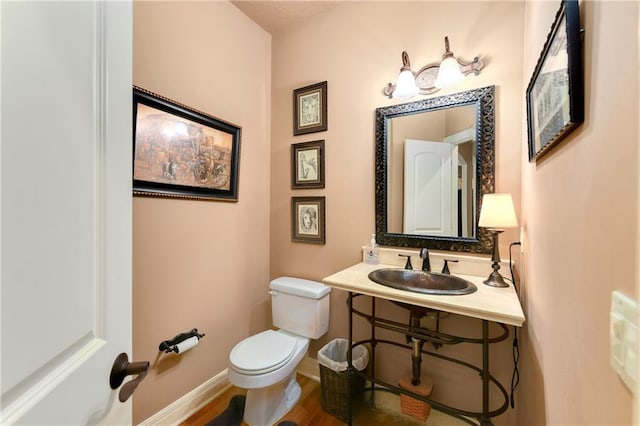 bathroom with toilet, baseboards, and a sink