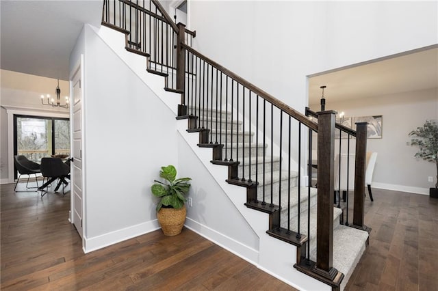 staircase with wood-type flooring and a notable chandelier