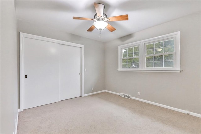 unfurnished bedroom featuring a closet, ceiling fan, and light colored carpet