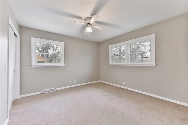 unfurnished bedroom featuring ceiling fan, light colored carpet, and a closet