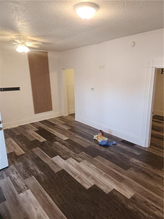 empty room featuring ceiling fan, dark wood-type flooring, and a textured ceiling