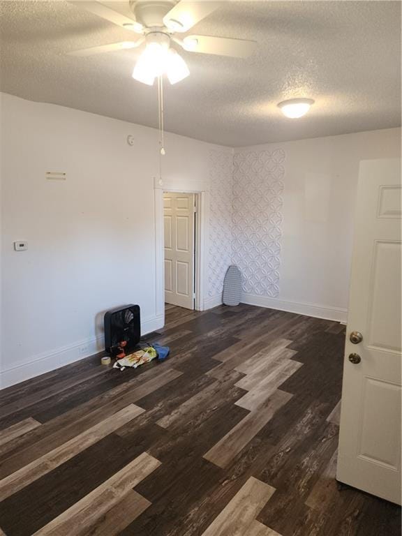 empty room with a textured ceiling, ceiling fan, and dark wood-type flooring