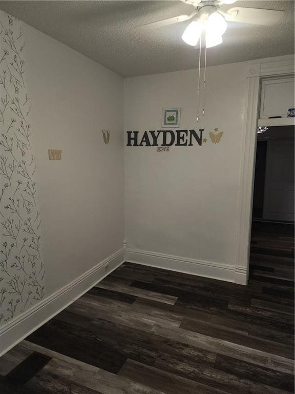 empty room with a textured ceiling, ceiling fan, and dark wood-type flooring