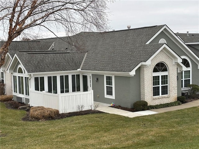 rear view of house featuring a sunroom and a lawn