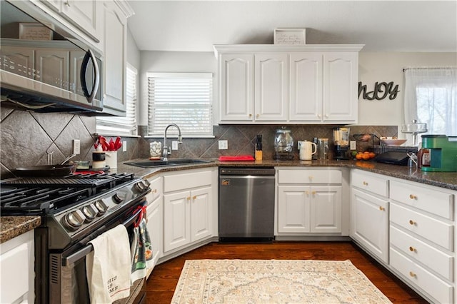 kitchen with dark stone countertops, stainless steel appliances, a wealth of natural light, and white cabinets