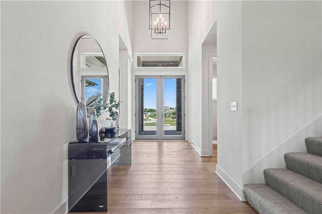 foyer entrance featuring french doors, a chandelier, hardwood / wood-style floors, and a high ceiling