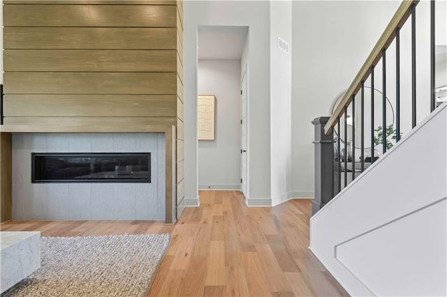 living room with a tile fireplace and light hardwood / wood-style floors