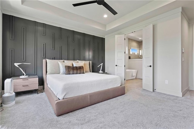 bedroom with light colored carpet, a raised ceiling, ceiling fan, and ensuite bathroom