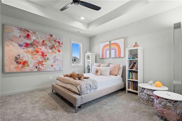 carpeted bedroom featuring a raised ceiling and ceiling fan