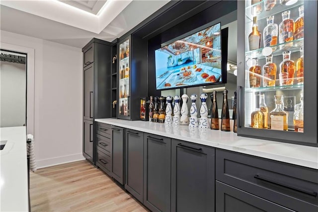 bar featuring light stone counters and light hardwood / wood-style flooring