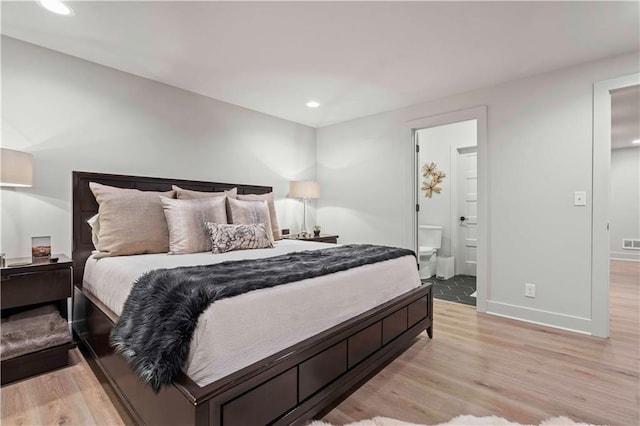 bedroom with connected bathroom and light wood-type flooring