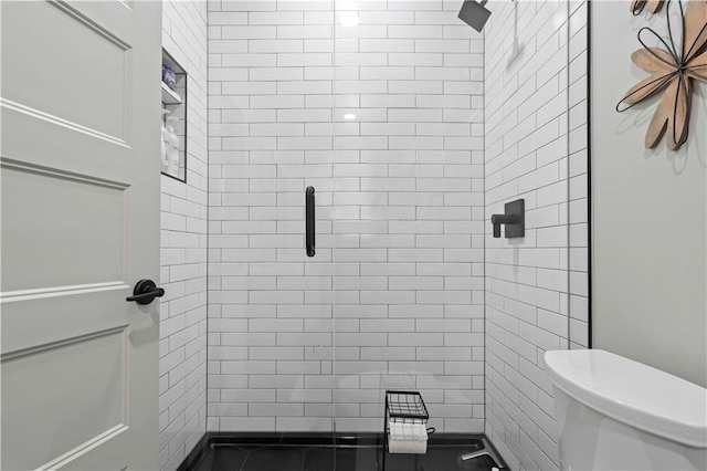 bathroom with a shower with shower door and toilet