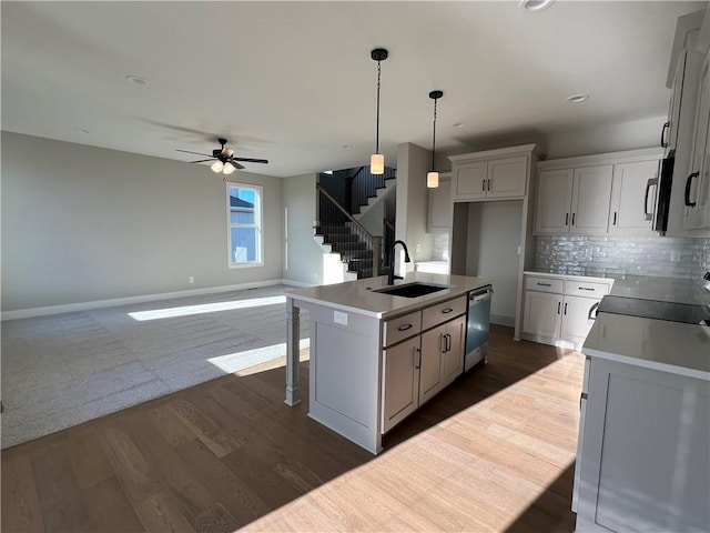 kitchen with sink, appliances with stainless steel finishes, a kitchen island with sink, wood-type flooring, and decorative light fixtures