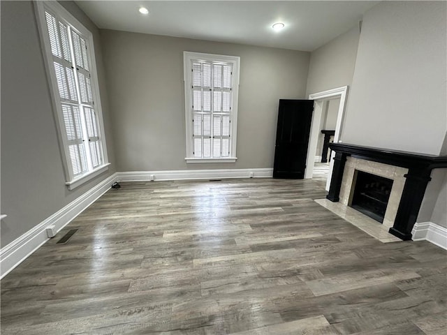 unfurnished living room with a premium fireplace, plenty of natural light, and wood-type flooring