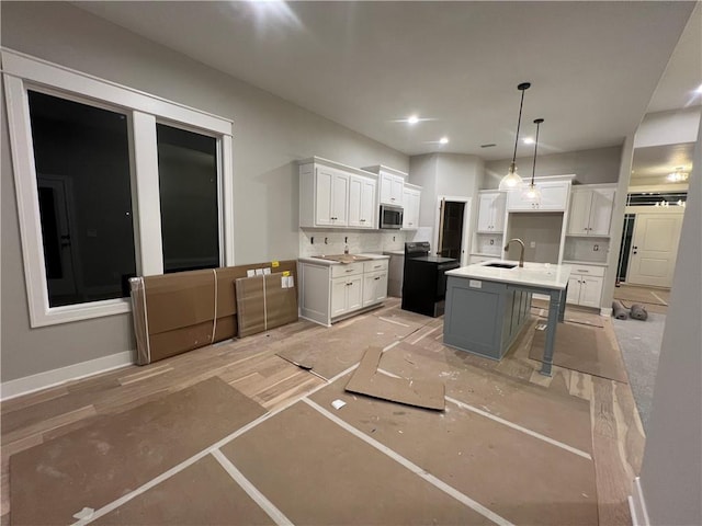 kitchen with sink, white cabinetry, a kitchen breakfast bar, pendant lighting, and a kitchen island with sink