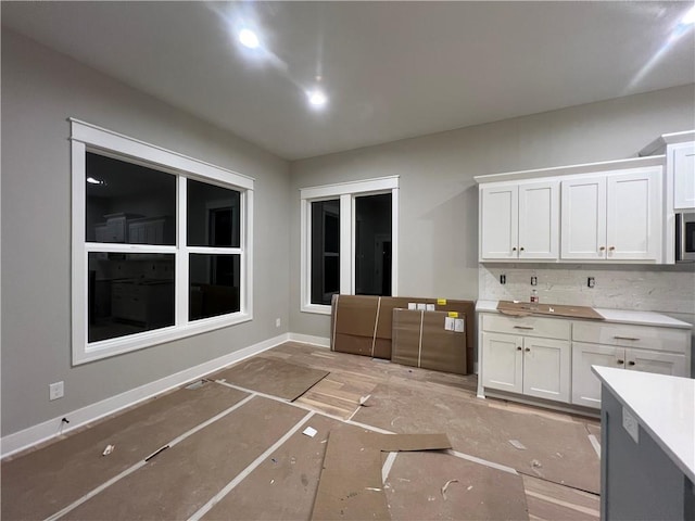 kitchen with tasteful backsplash and white cabinets