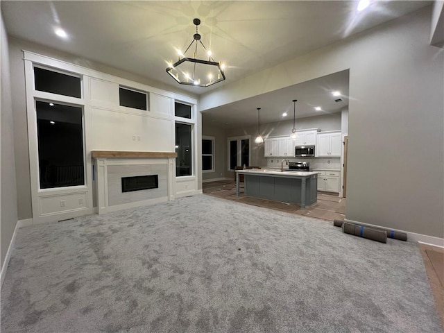 unfurnished living room featuring sink, light carpet, and an inviting chandelier