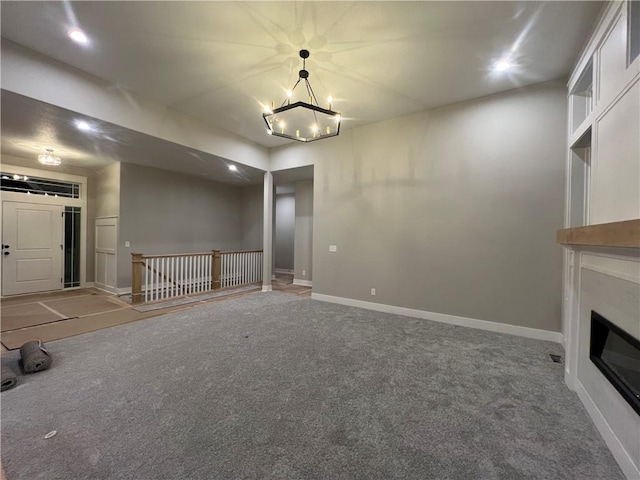 unfurnished living room featuring an inviting chandelier and carpet