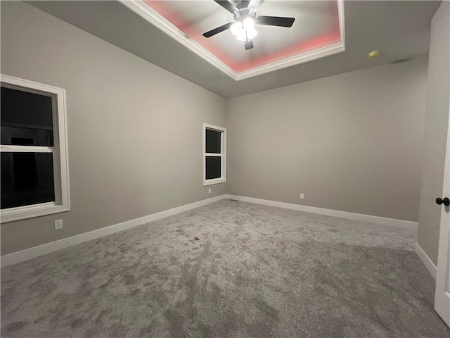 carpeted empty room with ceiling fan and a tray ceiling