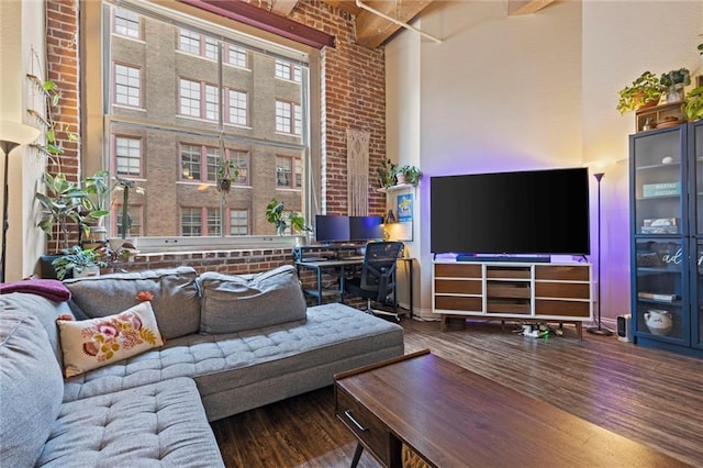 living area featuring beam ceiling, a high ceiling, and wood finished floors