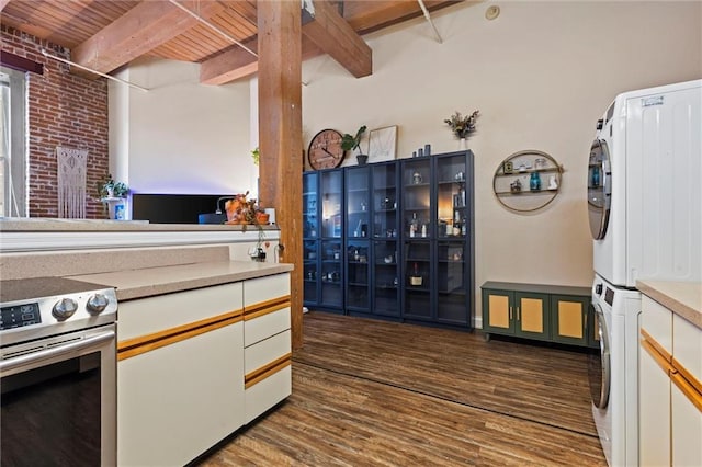 kitchen with beam ceiling, stainless steel range with electric stovetop, dark wood-style floors, and stacked washing maching and dryer