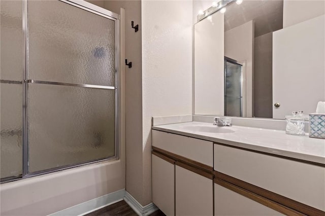 full bathroom with baseboards, shower / bath combination with glass door, and vanity