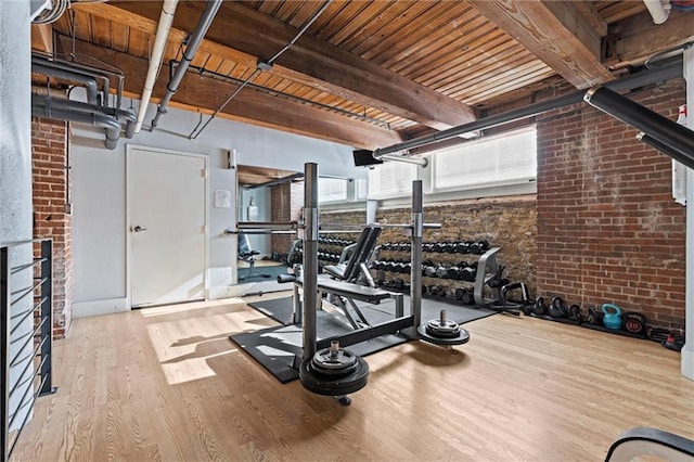 exercise area with wood ceiling, wood finished floors, and brick wall