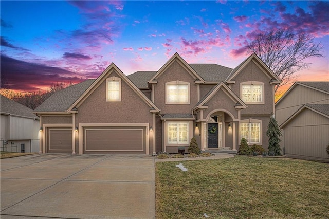 traditional-style home with a garage, concrete driveway, a front lawn, and stucco siding