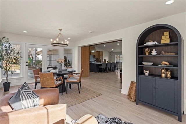 dining area featuring french doors, built in shelves, light hardwood / wood-style flooring, and a notable chandelier