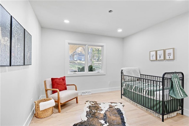 bedroom featuring hardwood / wood-style flooring and a nursery area