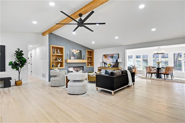 living room with ceiling fan with notable chandelier, light hardwood / wood-style floors, built in features, and vaulted ceiling with beams