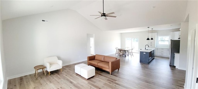 living room featuring ceiling fan, sink, high vaulted ceiling, and light hardwood / wood-style floors