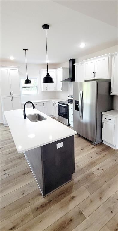 kitchen featuring sink, wall chimney range hood, pendant lighting, white cabinets, and appliances with stainless steel finishes