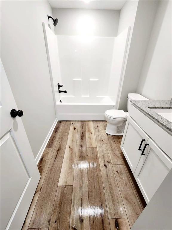 full bathroom featuring hardwood / wood-style floors, vanity, toilet, and shower / bathing tub combination