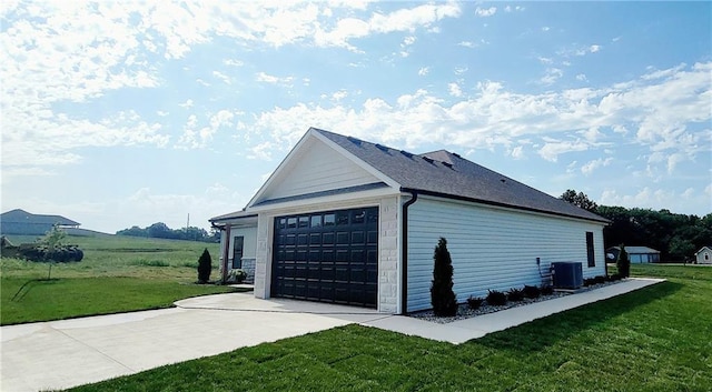 view of side of property featuring a lawn, a garage, and central air condition unit