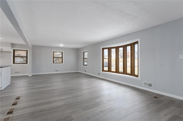 unfurnished living room with dark wood-type flooring and a textured ceiling