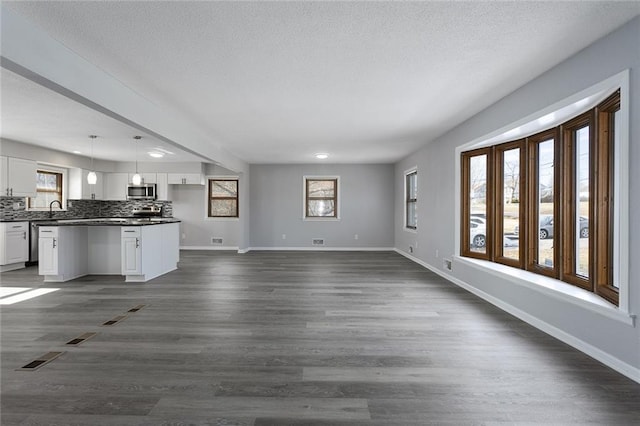 unfurnished living room featuring sink, dark wood-type flooring, and a textured ceiling