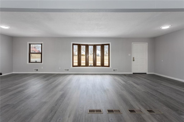 unfurnished living room with plenty of natural light, dark hardwood / wood-style flooring, and a textured ceiling