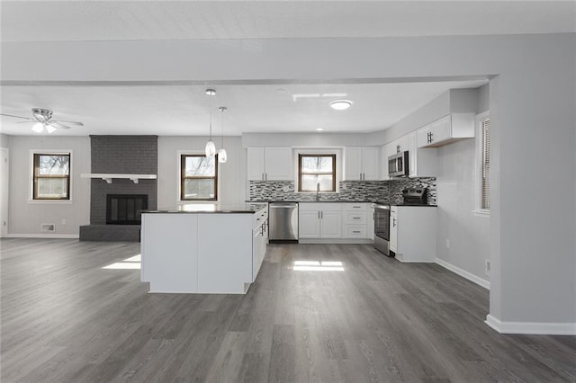 kitchen with white cabinetry, decorative light fixtures, a wealth of natural light, stainless steel appliances, and backsplash