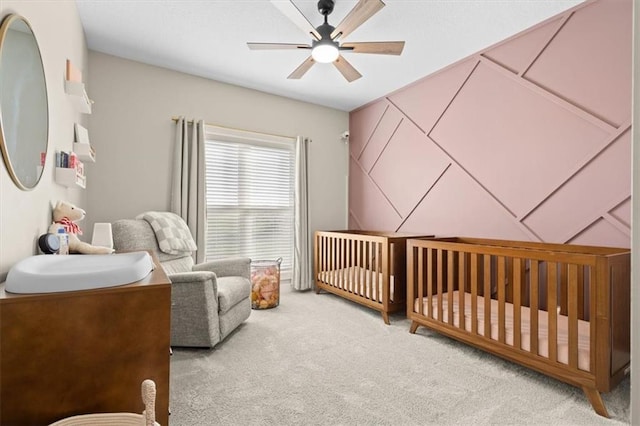 bedroom with ceiling fan, carpet floors, and a nursery area