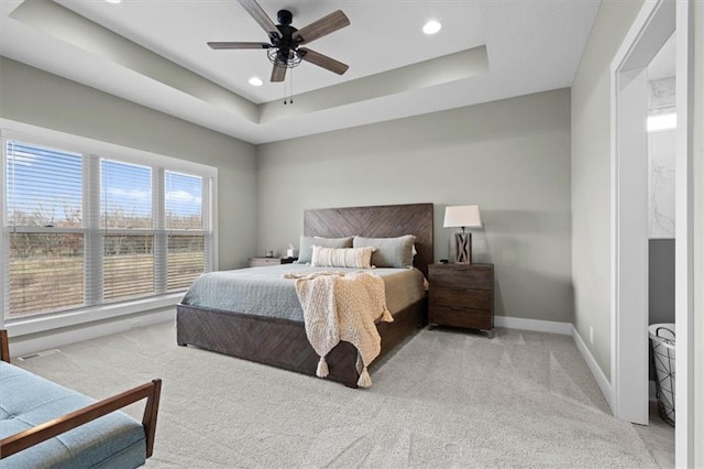 bedroom featuring light carpet, a raised ceiling, and ceiling fan