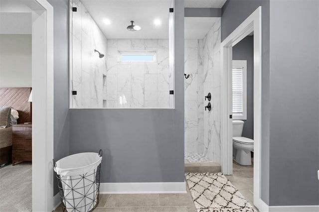 bathroom featuring a tile shower, a wealth of natural light, tile patterned flooring, and toilet