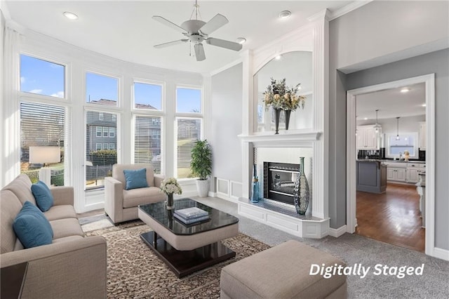 carpeted living area featuring a fireplace, recessed lighting, ornamental molding, ceiling fan, and baseboards