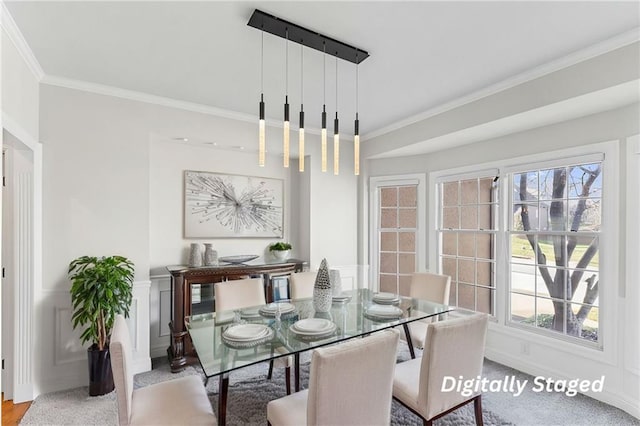 dining area featuring a decorative wall, wainscoting, and crown molding