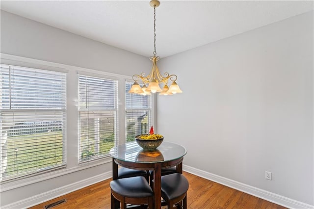 dining room with baseboards, visible vents, a chandelier, and wood finished floors