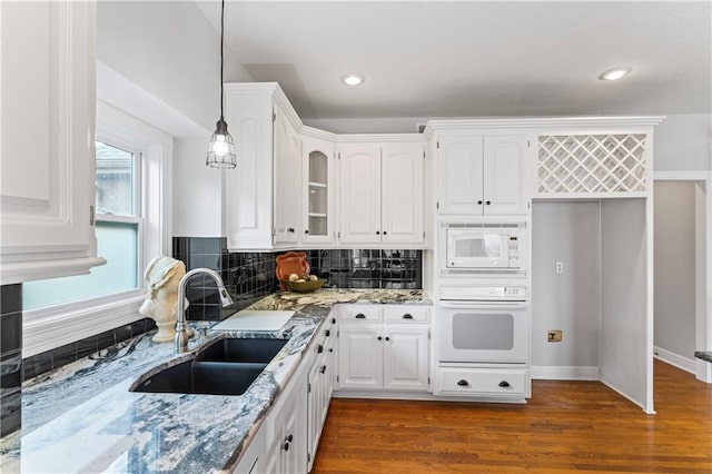 kitchen featuring decorative light fixtures, white cabinetry, a sink, light stone countertops, and white appliances