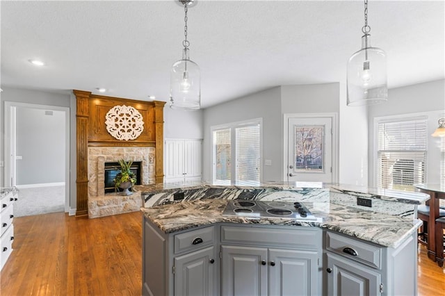 kitchen featuring a kitchen island, open floor plan, decorative light fixtures, and stovetop